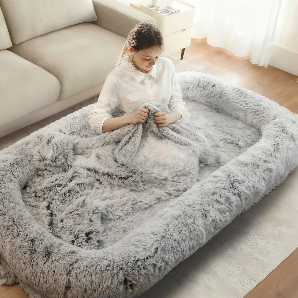 Woman sitting up in the gray shag bed with a blanket over her legs