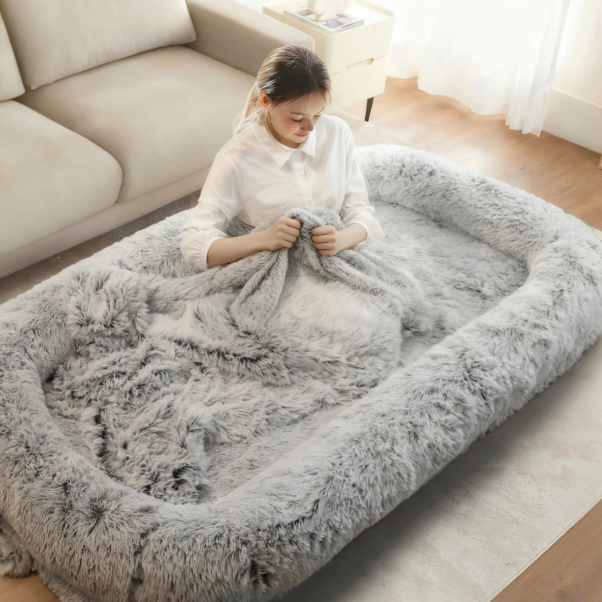 Woman sitting up in the gray shag bed with a blanket over her legs