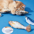 Fluffy orange cat hugging three plush fish, with the 150 mAh battery unit shown